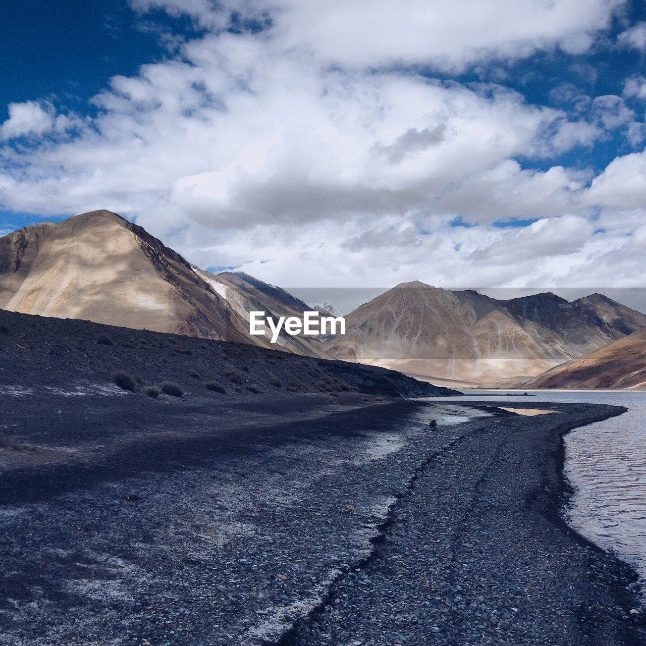 Road by mountains against cloudy sky at ladakh