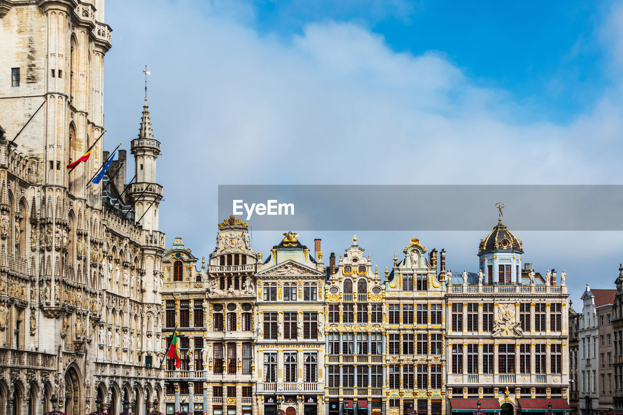 LOW ANGLE VIEW OF BUILDINGS IN CITY AGAINST CLOUDY SKY