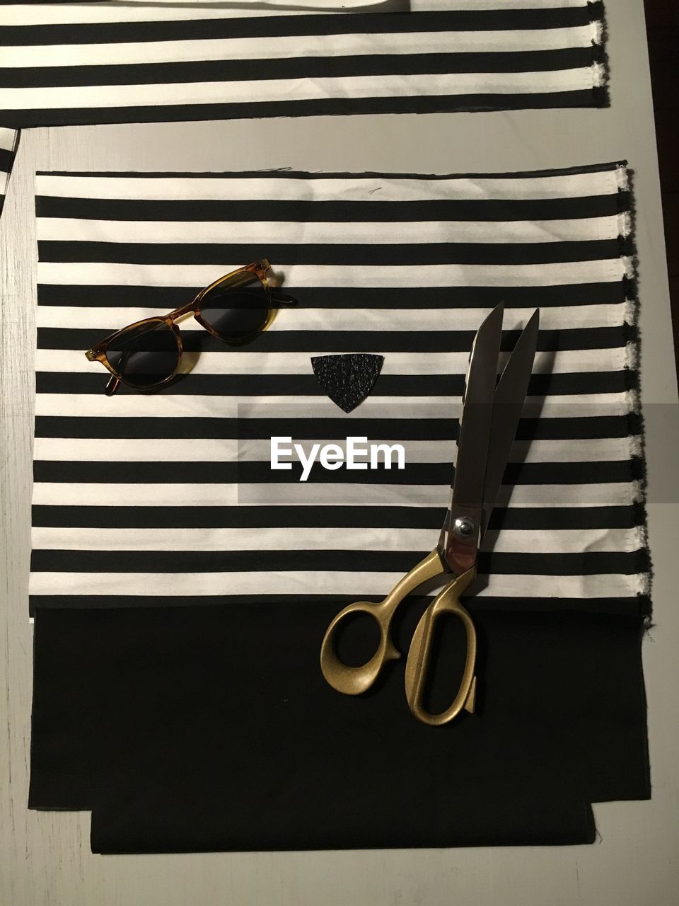 High angle view of scissors and sunglasses on fabric