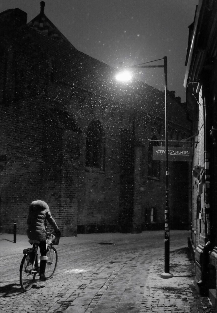 MAN CYCLING ON ILLUMINATED AT NIGHT