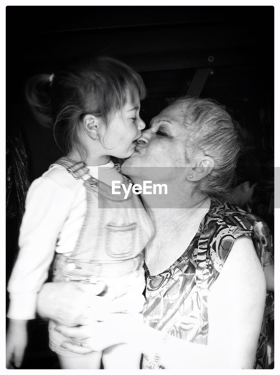 CLOSE-UP OF MOTHER AND DAUGHTER AGAINST CURTAIN AT HOME