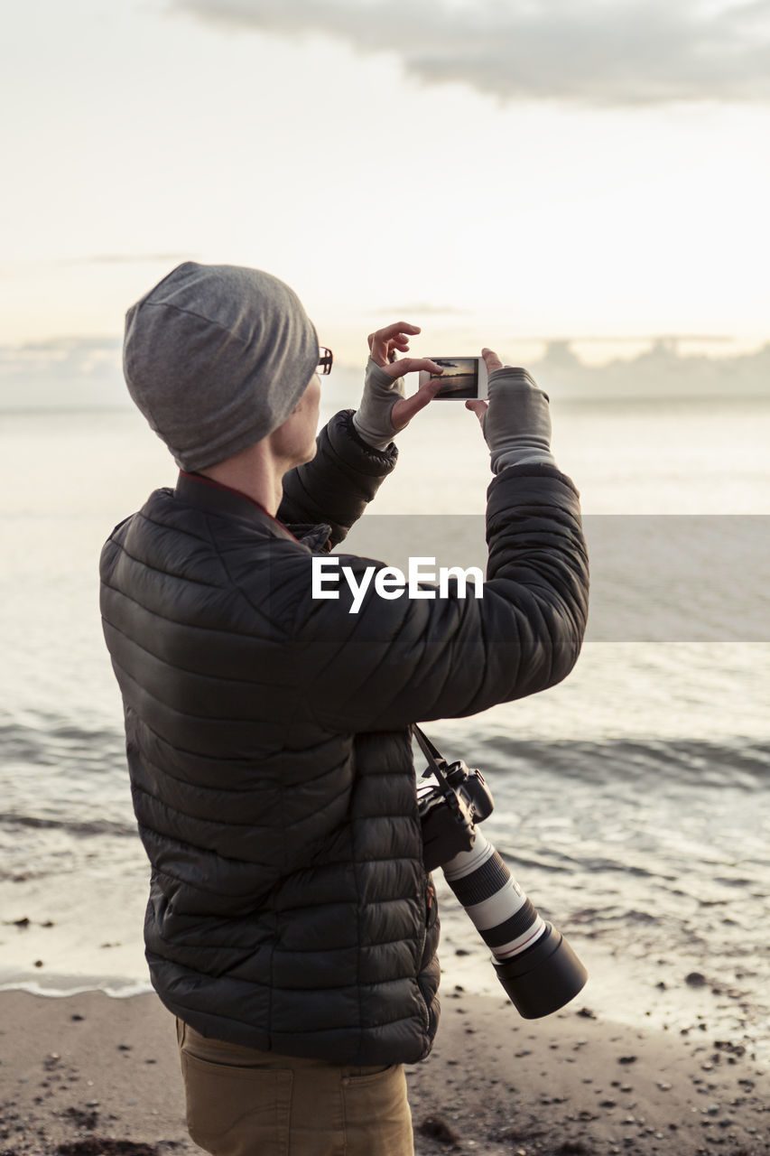 Hiker photographing through smart phone at beach