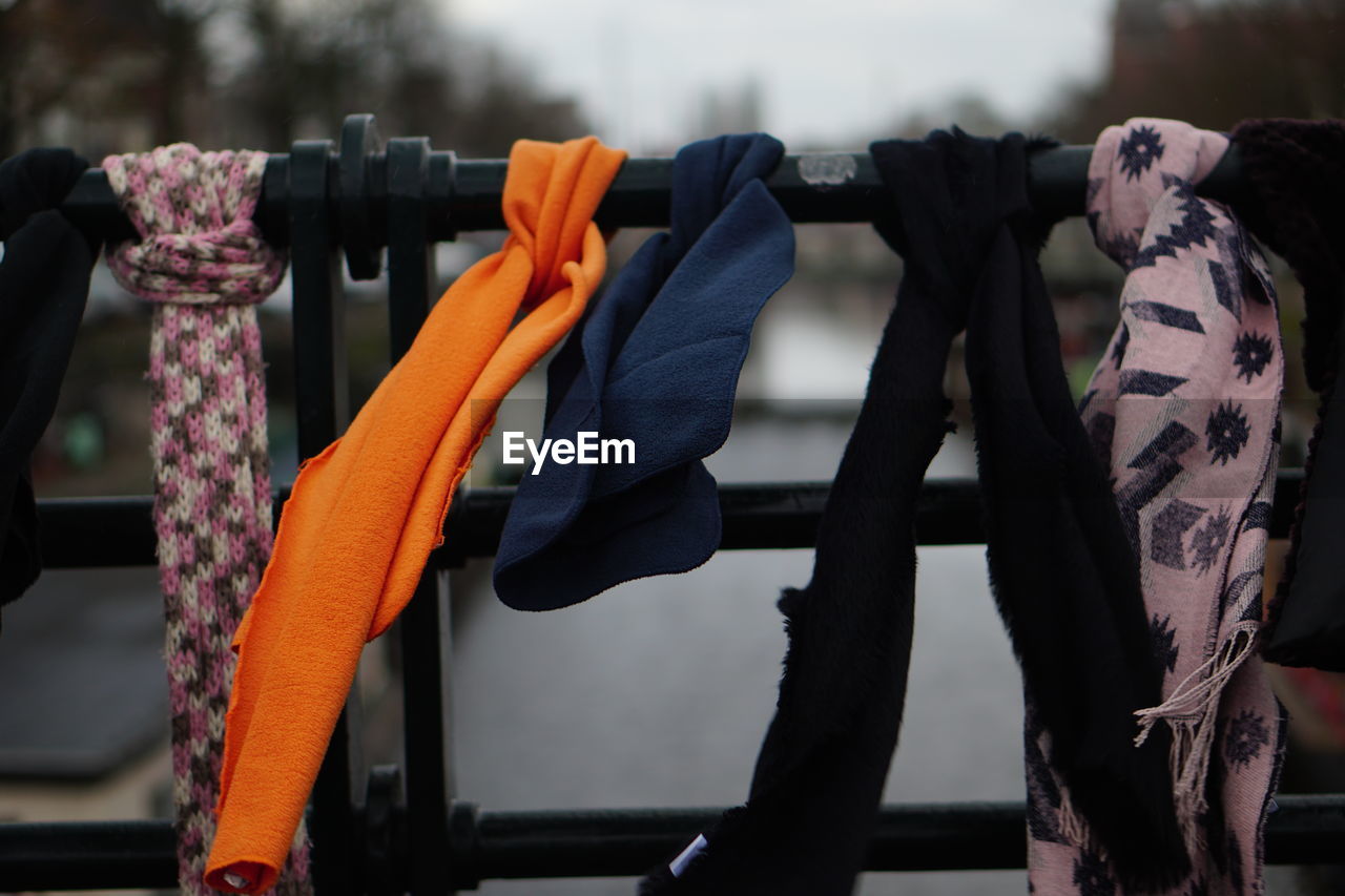 CLOSE-UP OF CLOTHES HANGING ON METAL RAILING BY RACK