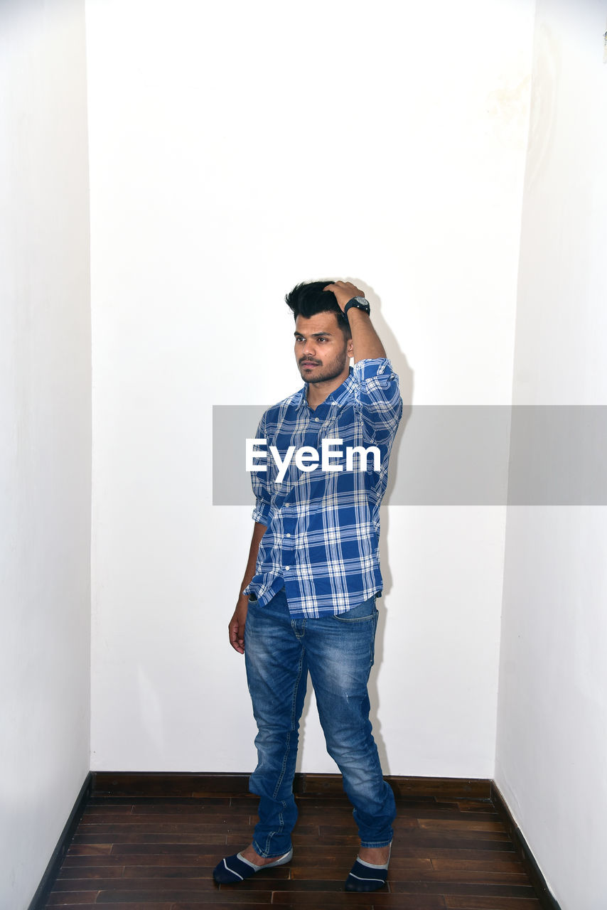 YOUNG MAN STANDING AGAINST WALL