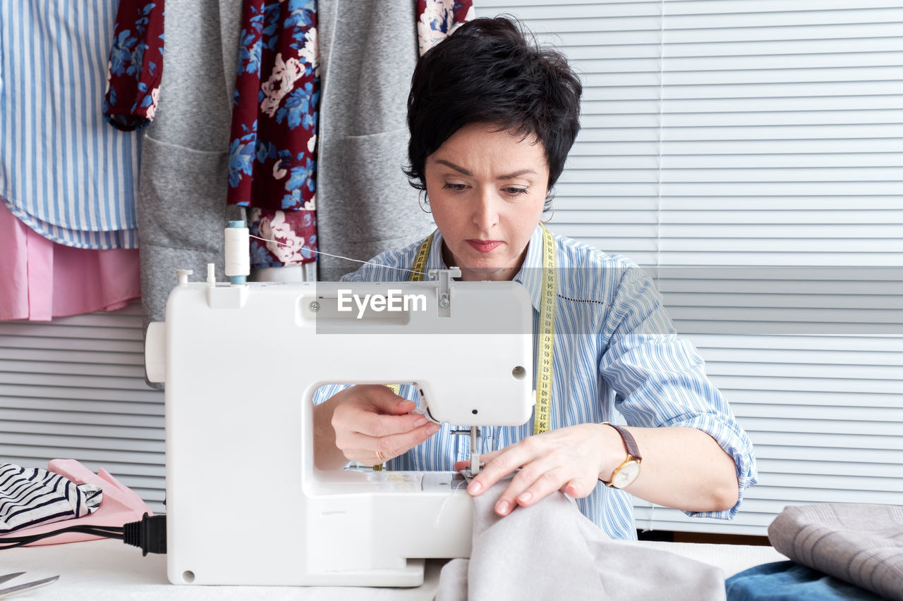 Craftswoman sewing textile on machine at workshop