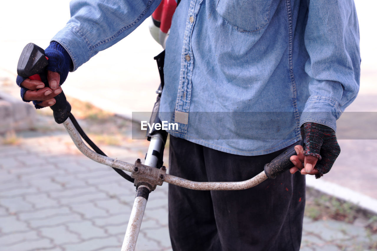 Midsection of man holding metal