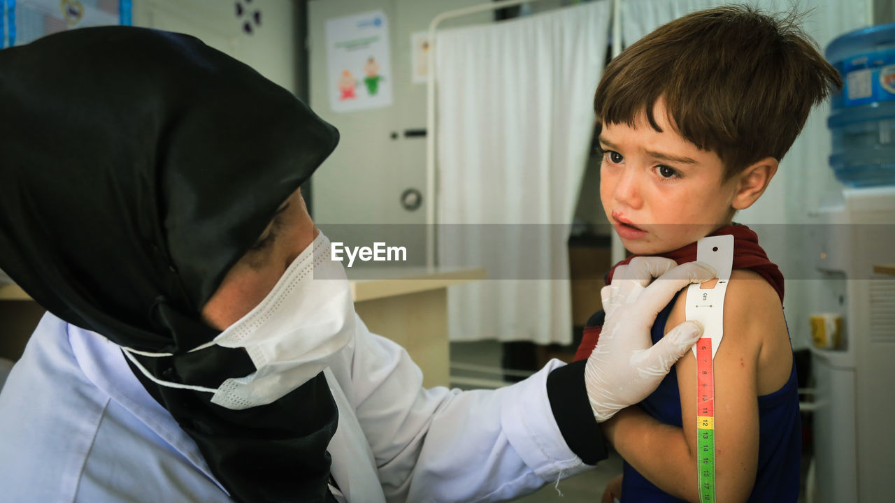 Doctor wearing mask examining patient at clinic