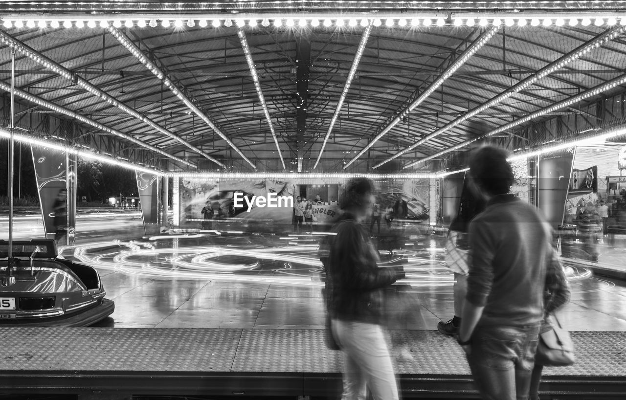 PEOPLE STANDING ON ILLUMINATED WALKWAY