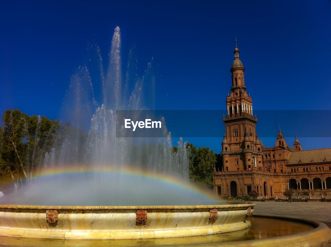 Rainbow on fountain at plaza de espana against clear blue sky