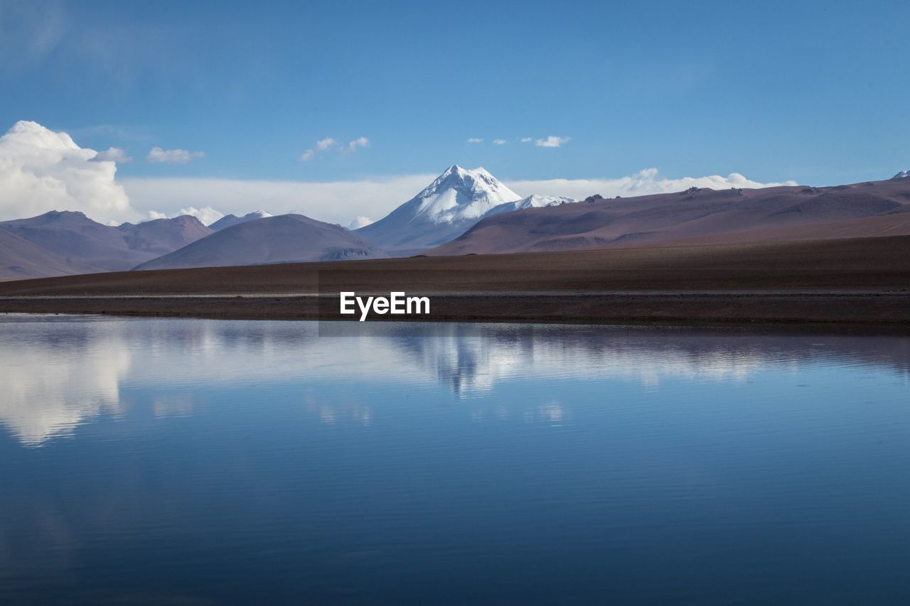 Scenic view of lake and mountains against blue sky