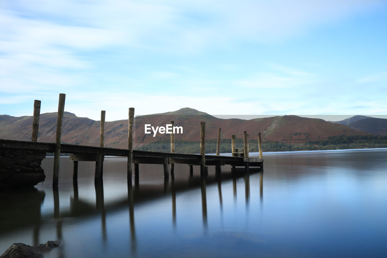 WOODEN POST IN LAKE AGAINST SKY