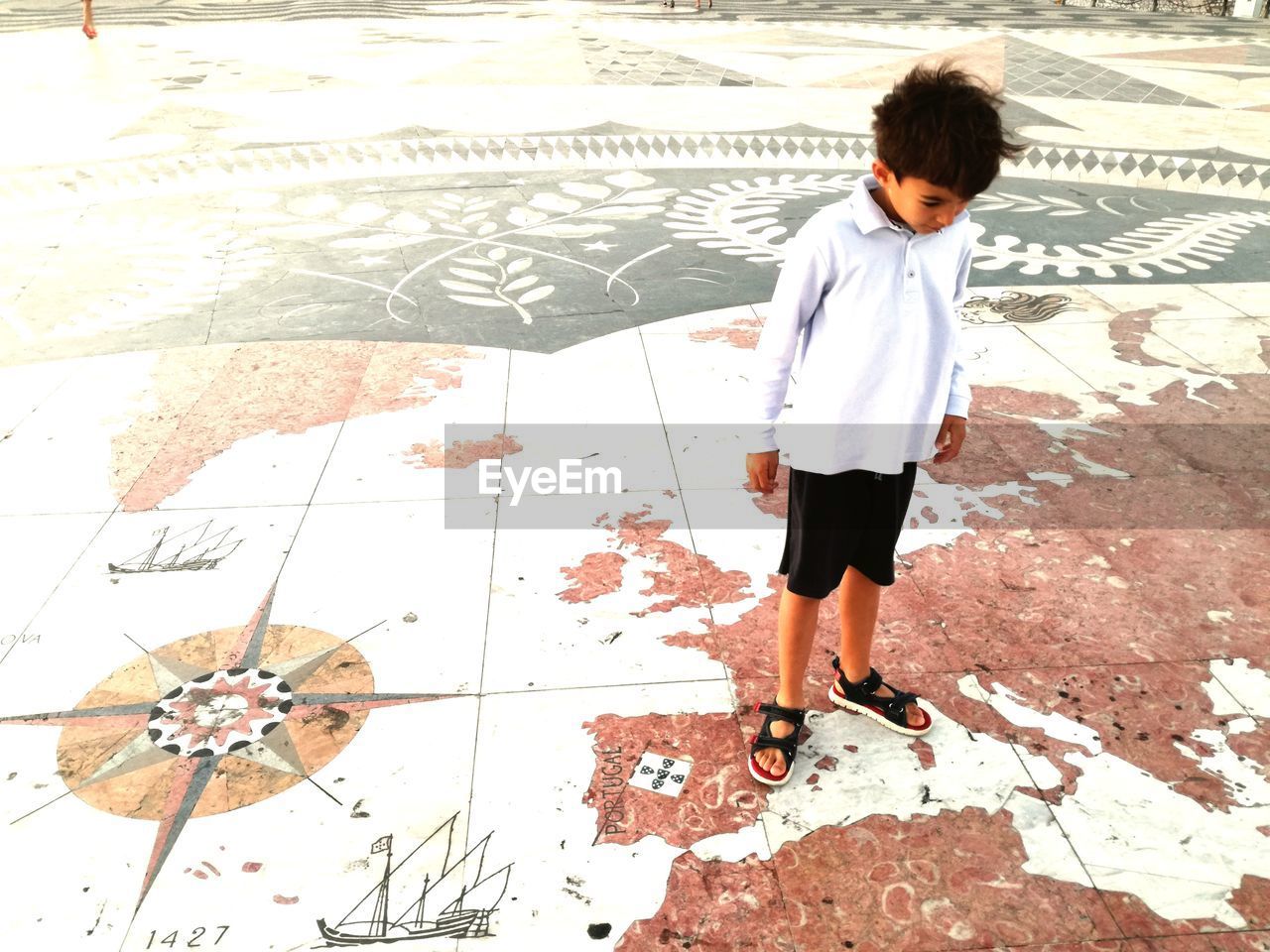 Full length of boy standing on map patterned floor at playground