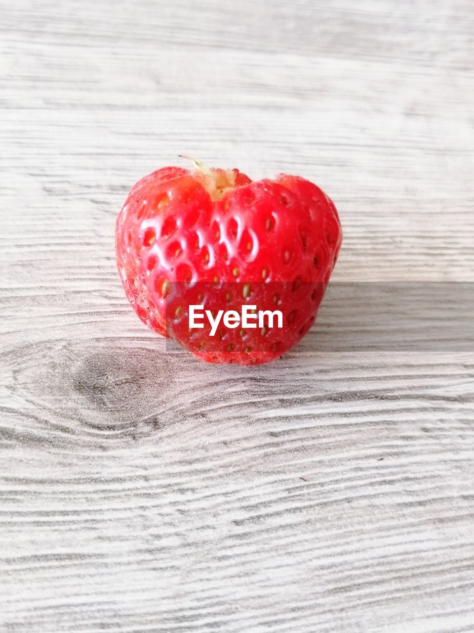 CLOSE-UP OF STRAWBERRY ON TABLE AGAINST GRAY BACKGROUND