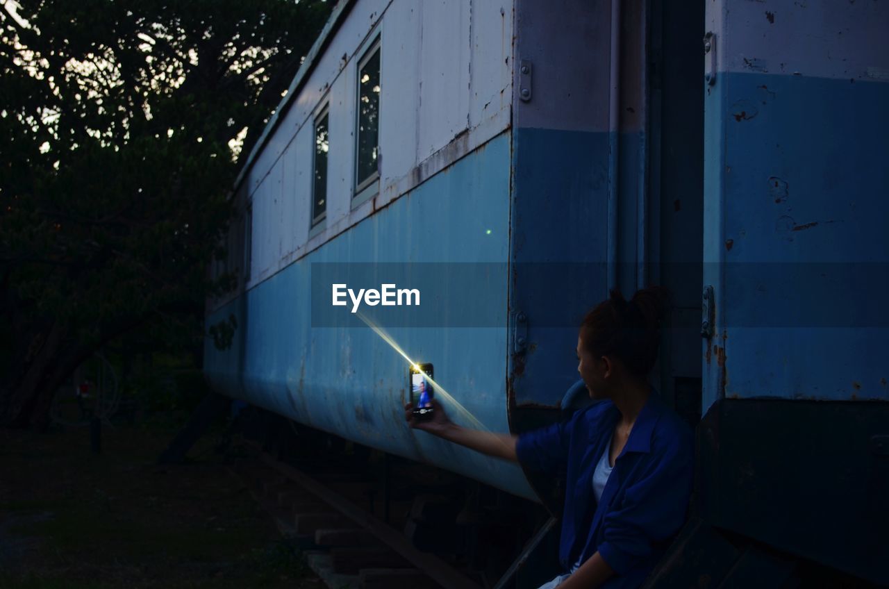 REAR VIEW OF WOMAN SITTING ON RAILROAD TRACKS