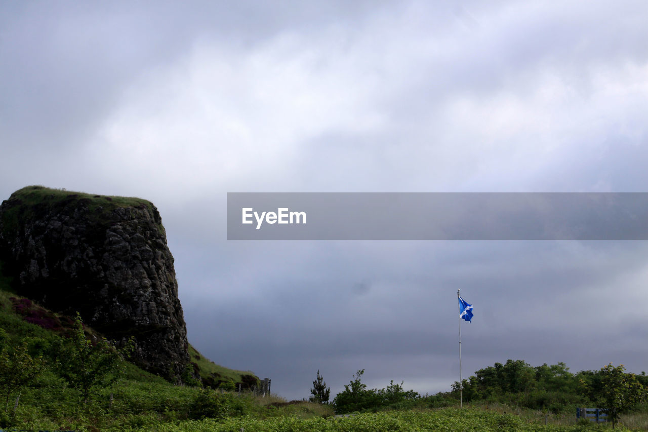 Flag by cliff against sky