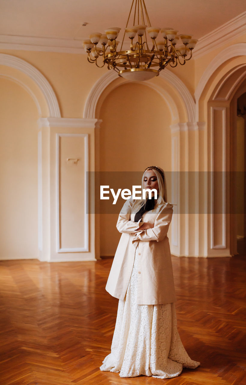 Beautiful teenage girl wearing wedding dress while standing on floor