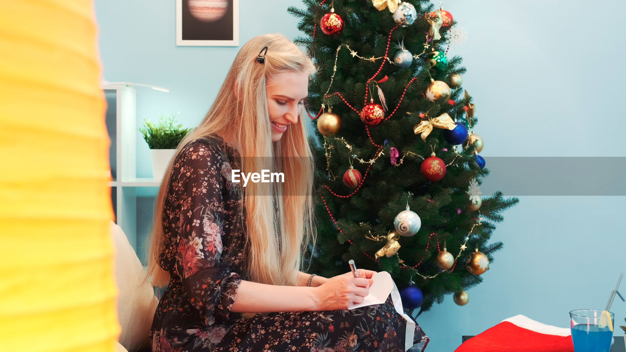 rear view of woman with christmas tree at home