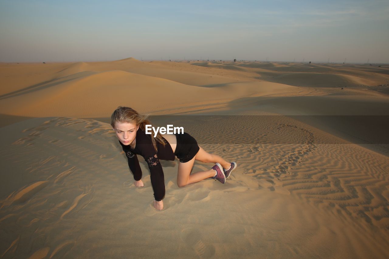 High angle view of girl looking away crawling on desert