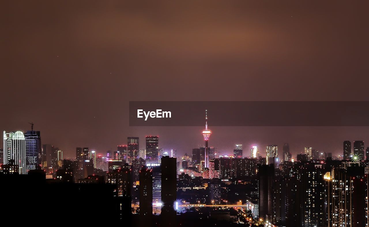 Illuminated buildings against sky at night