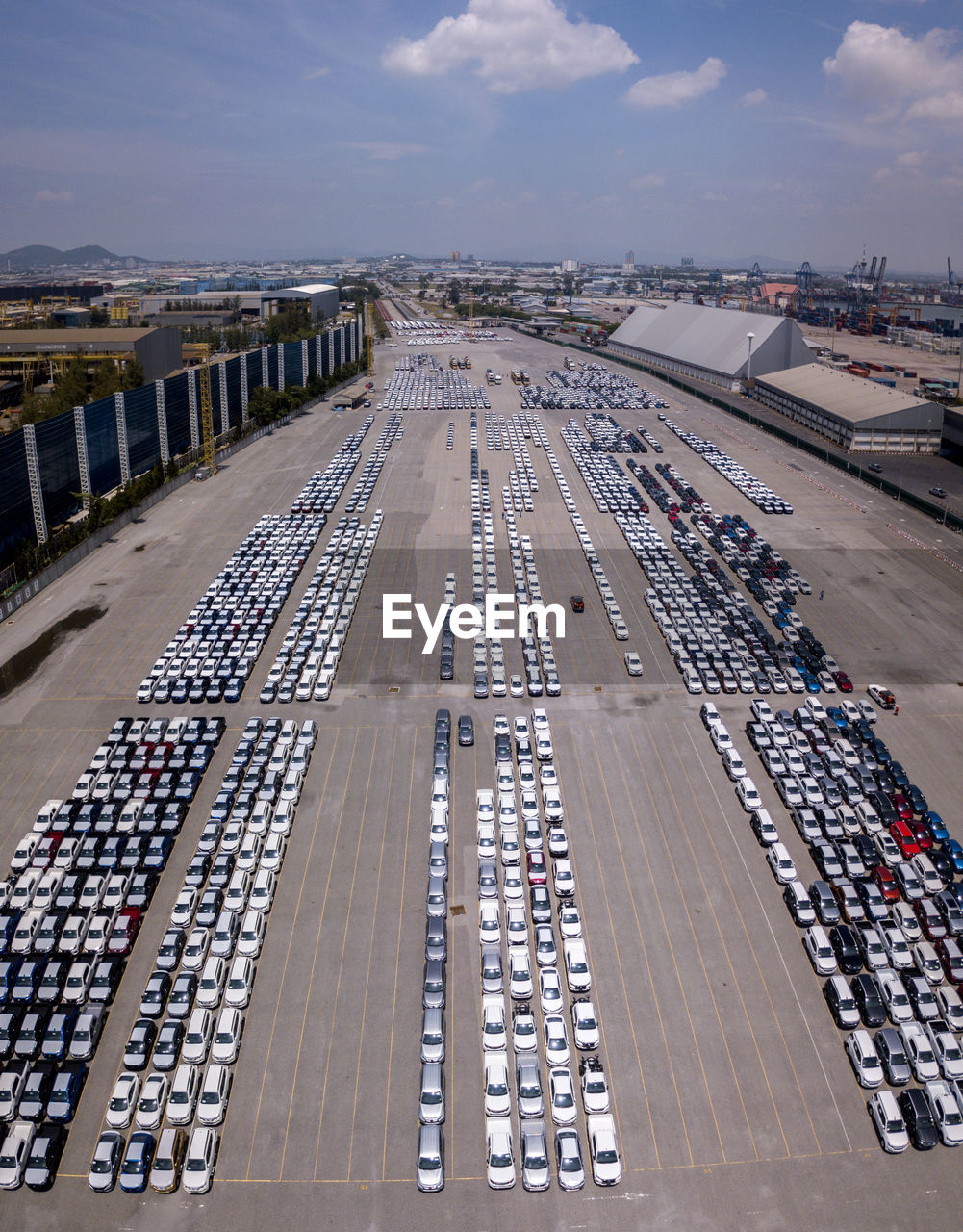 Aerial logistics commercial vehicles waiting to be load on to a car carrier ship at dockyard