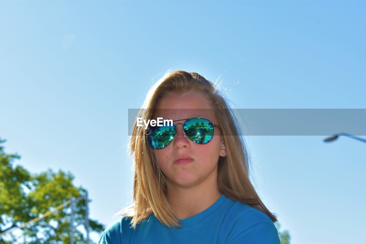 PORTRAIT OF GIRL WEARING SUNGLASSES AGAINST CLEAR SKY