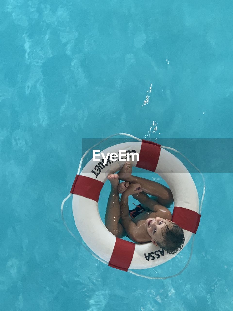 High angle view of boy in swimming pool with lifebuoy