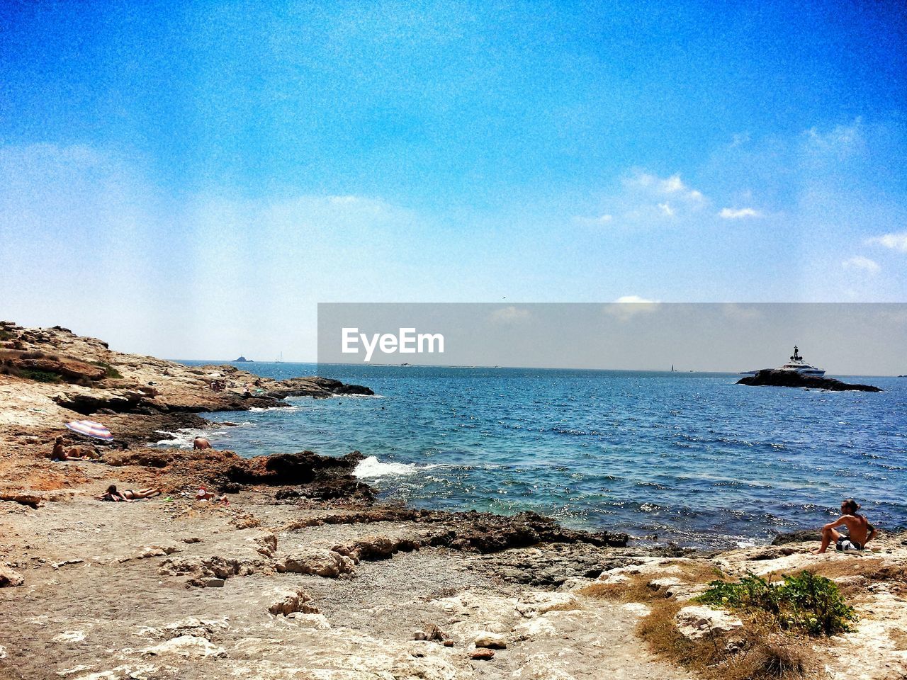 People on beach against sky during sunny day