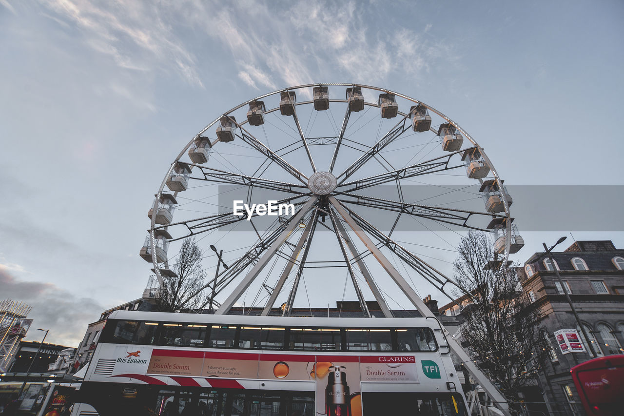 LOW ANGLE VIEW OF FERRIS WHEEL IN CITY AGAINST SKY