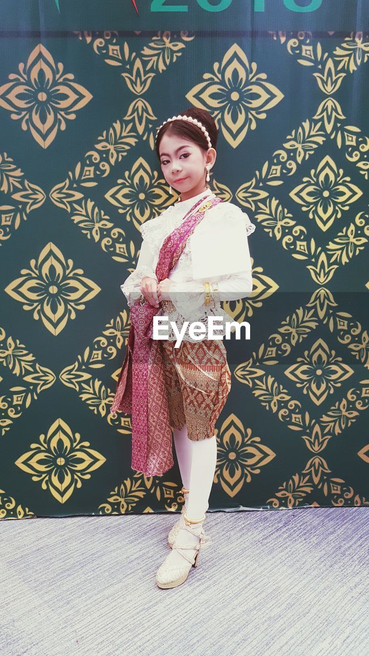 Portrait of girl standing against wallpaper 