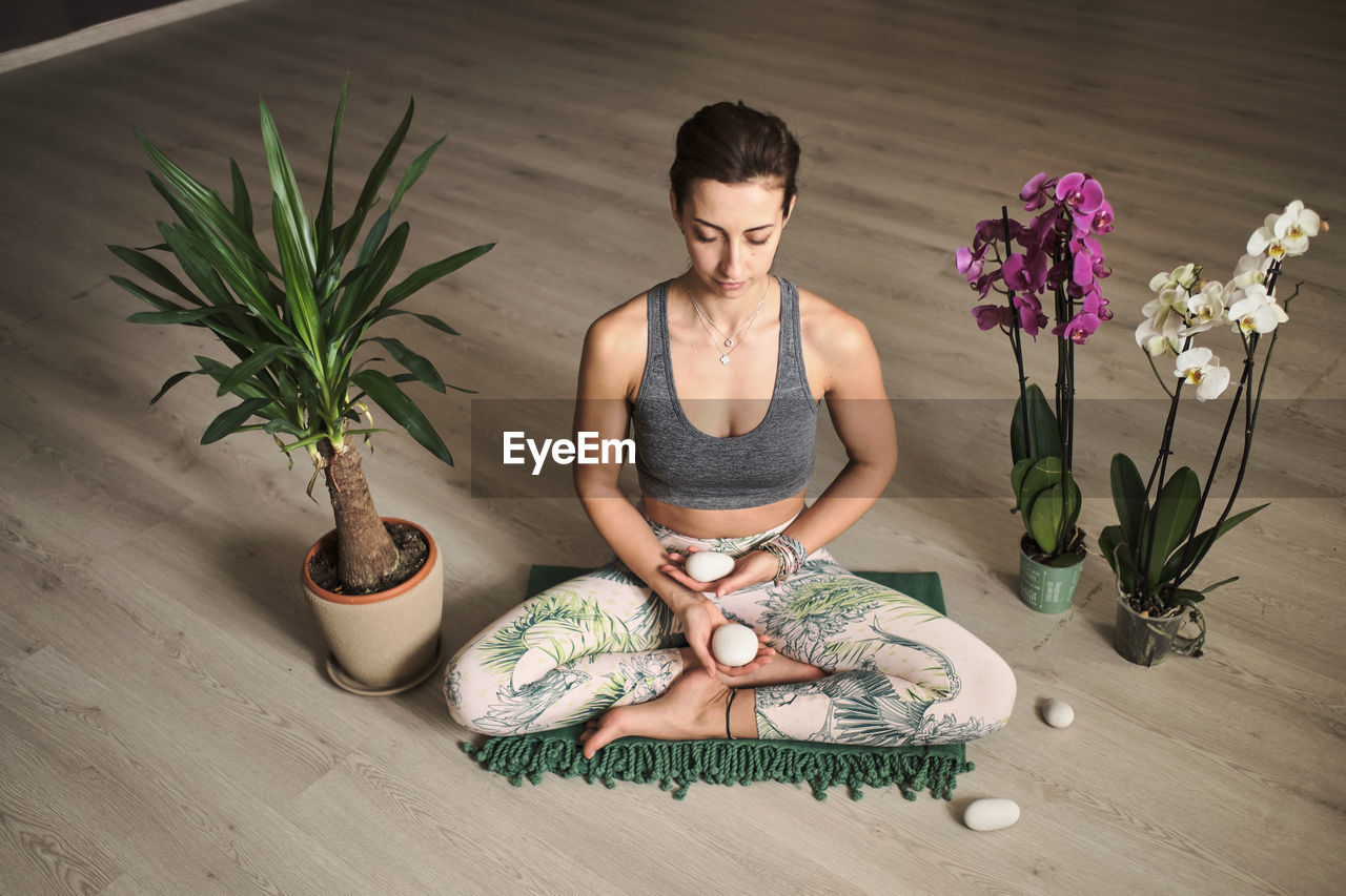 Woman doing meditation at yoga studio in the middle of flowers