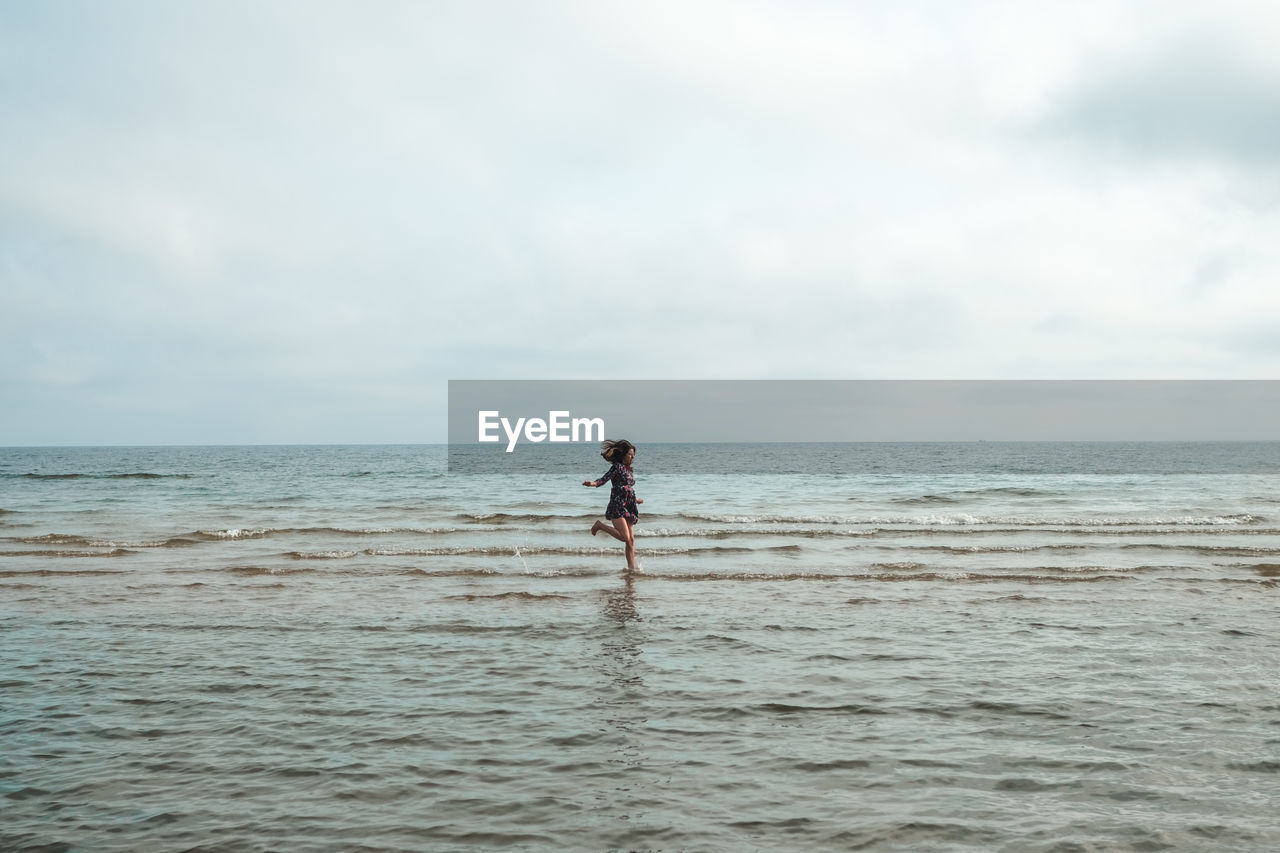 Woman running on beach against sky