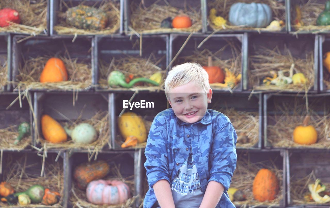 PORTRAIT OF HAPPY BOY WITH PUMPKINS IN MARKET