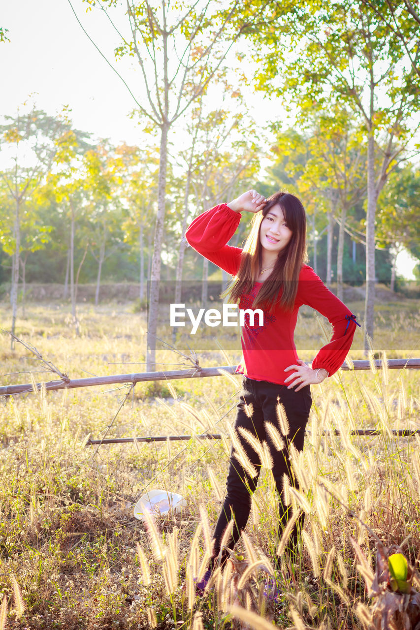 YOUNG WOMAN WITH RED UMBRELLA ON FIELD