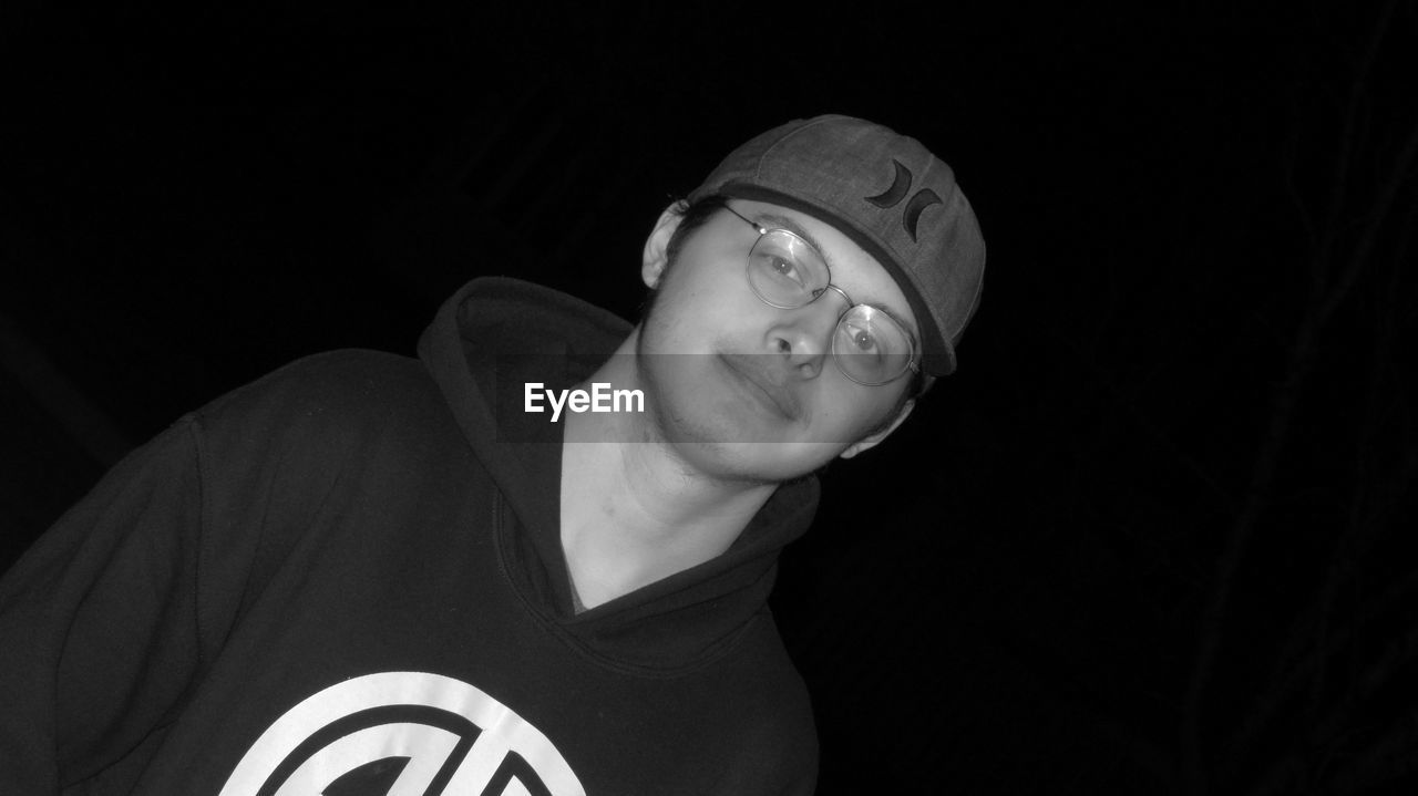 PORTRAIT OF YOUNG MAN WEARING MASK AGAINST BLACK BACKGROUND