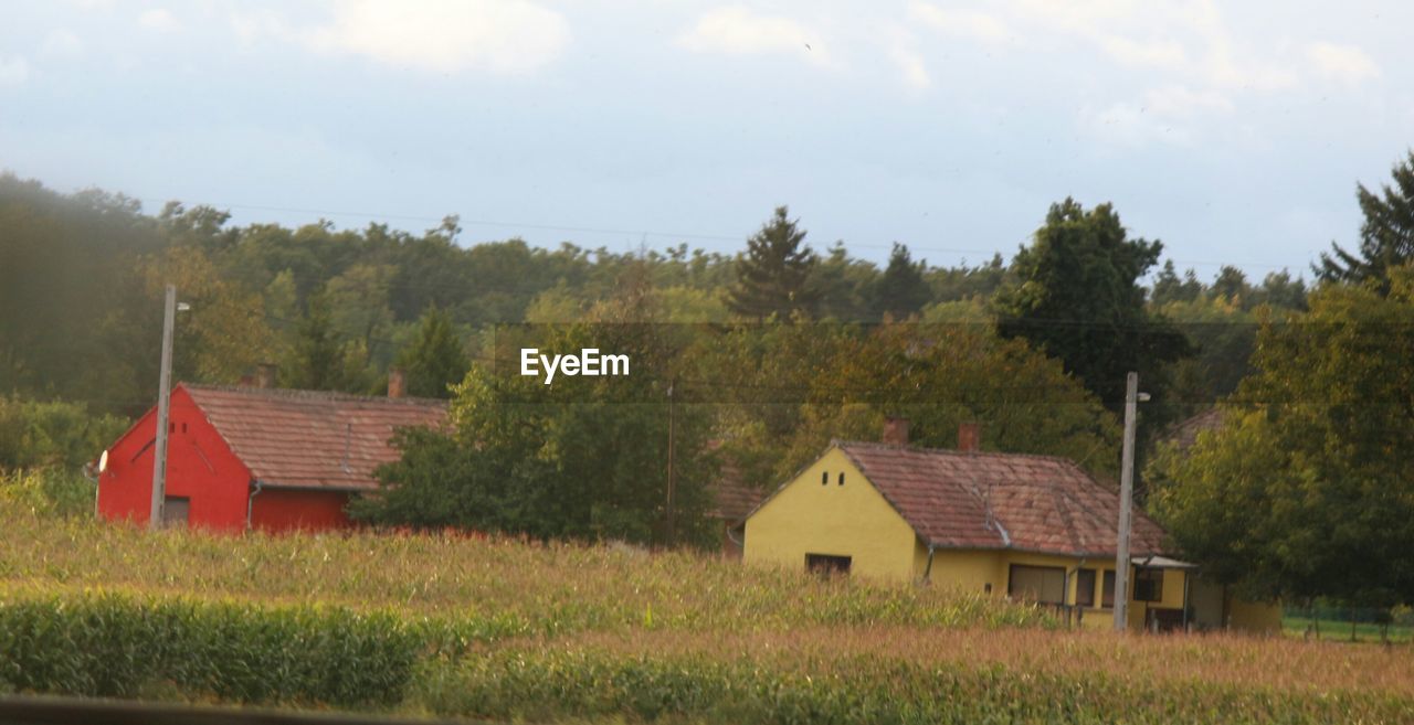 HOUSES ON FIELD AGAINST SKY