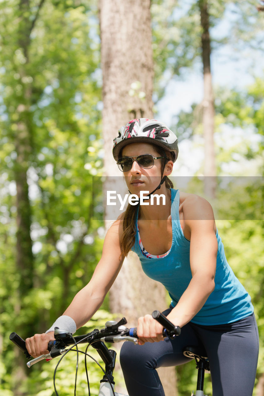 Low angle view of woman riding bicycle in forest