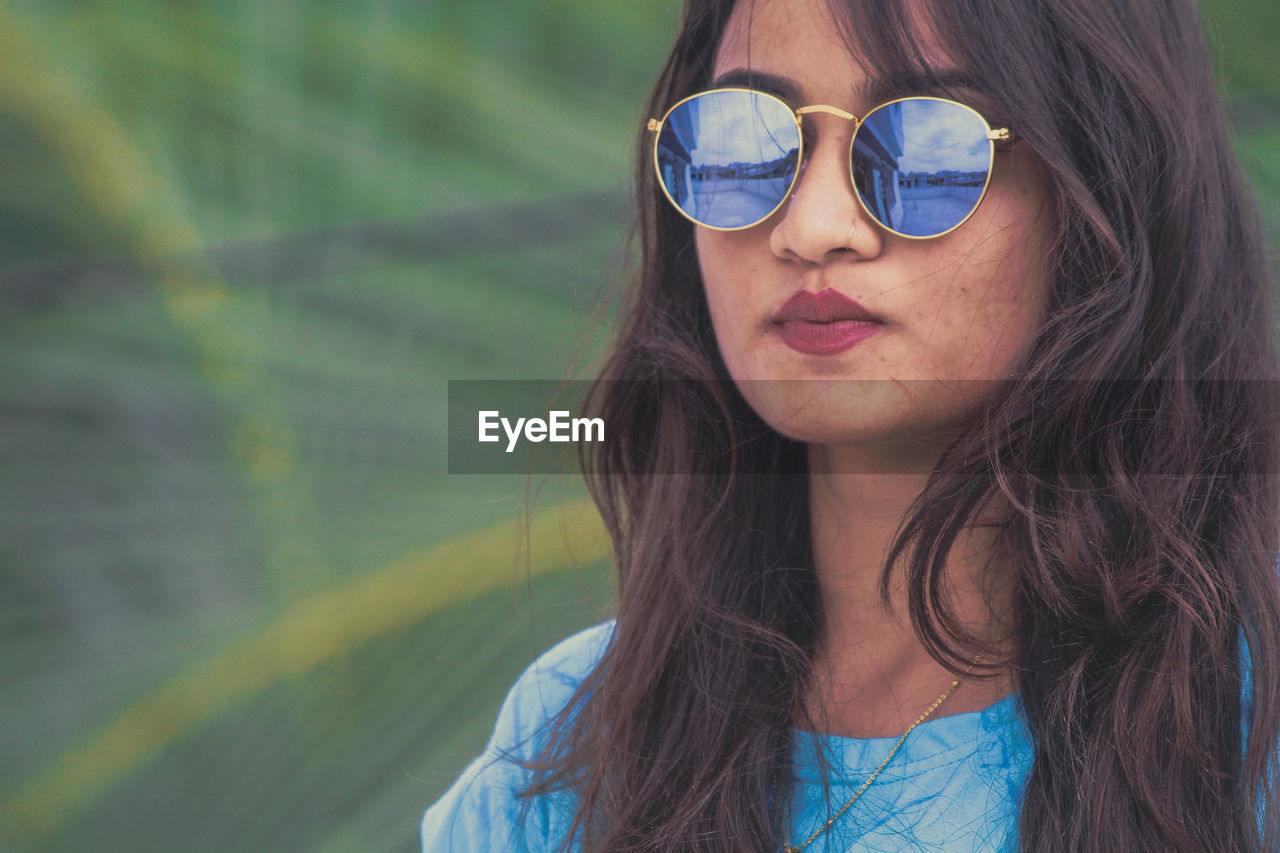 Close-up portrait of woman wearing sunglasses while standing outdoors