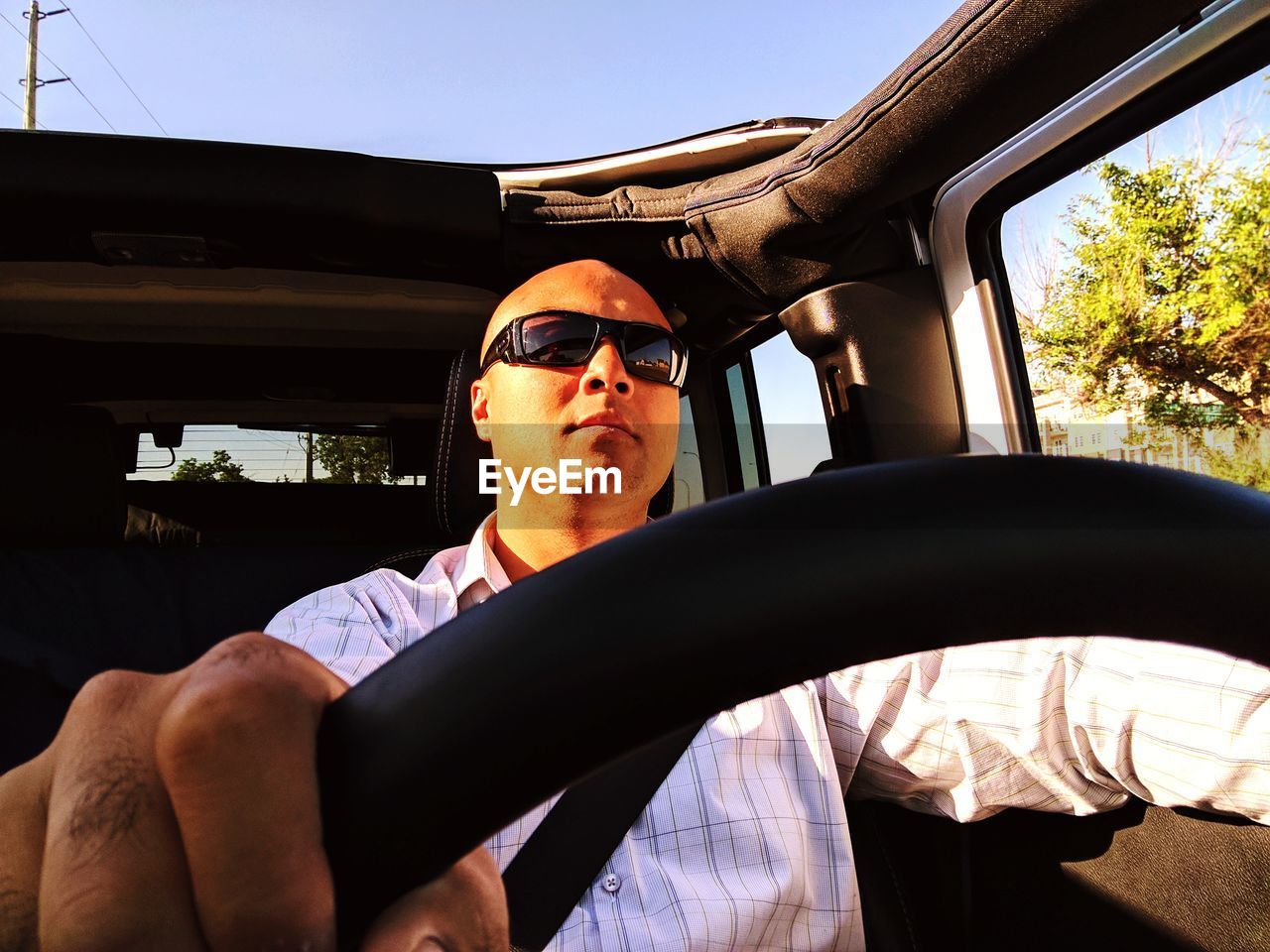 Bald man wearing sunglasses while driving car