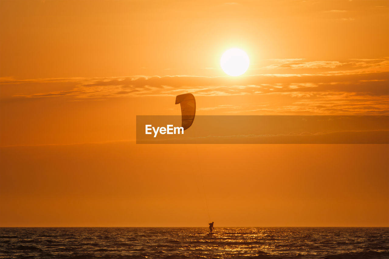 Kiteboarding kitesurfing kiteboarder kitesurfer kites silhouette in the ocean on sunset