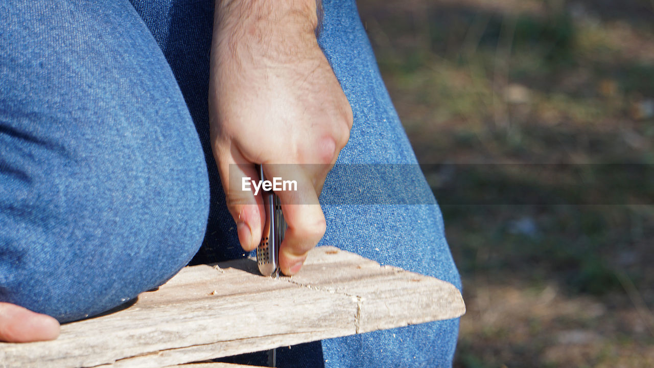 blue, hand, one person, human leg, adult, limb, jeans, casual clothing, men, close-up, day, midsection, focus on foreground, nature, human limb, clothing, lifestyles, outdoors, holding, footwear, leisure activity, low section, wood, person, denim