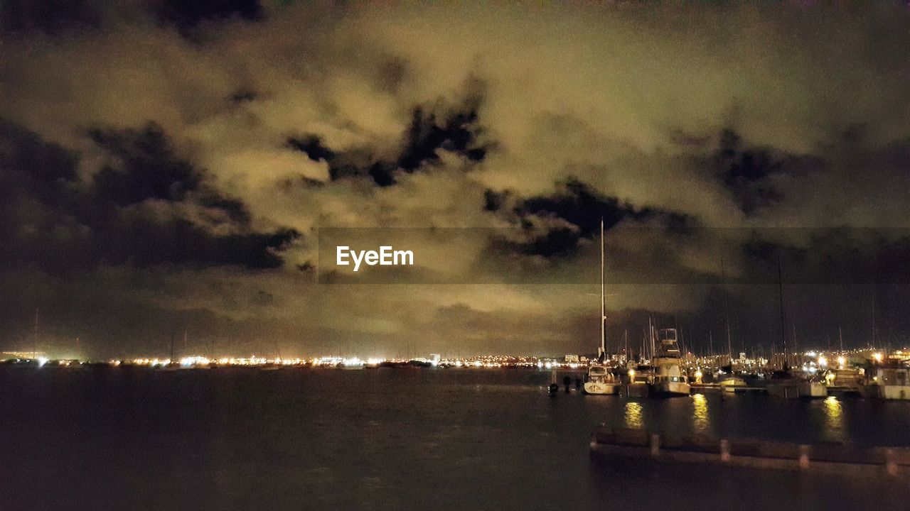 VIEW OF ILLUMINATED CITY AGAINST CLOUDY SKY