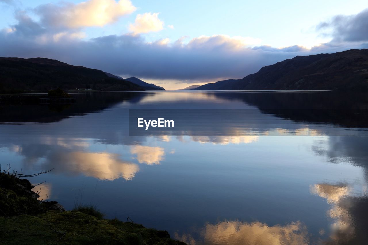 Scenic view of lake by mountains against sky