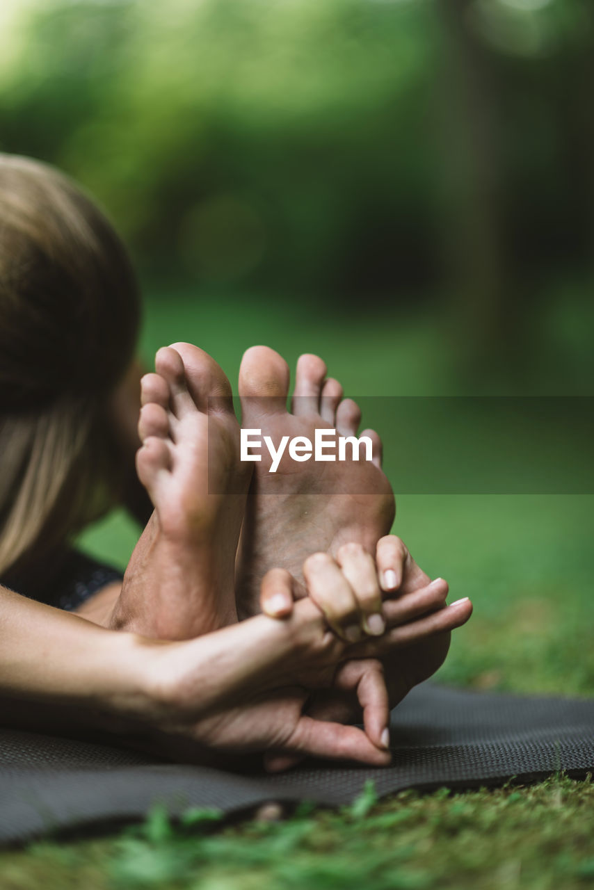 Low section of woman doing yoga in garden