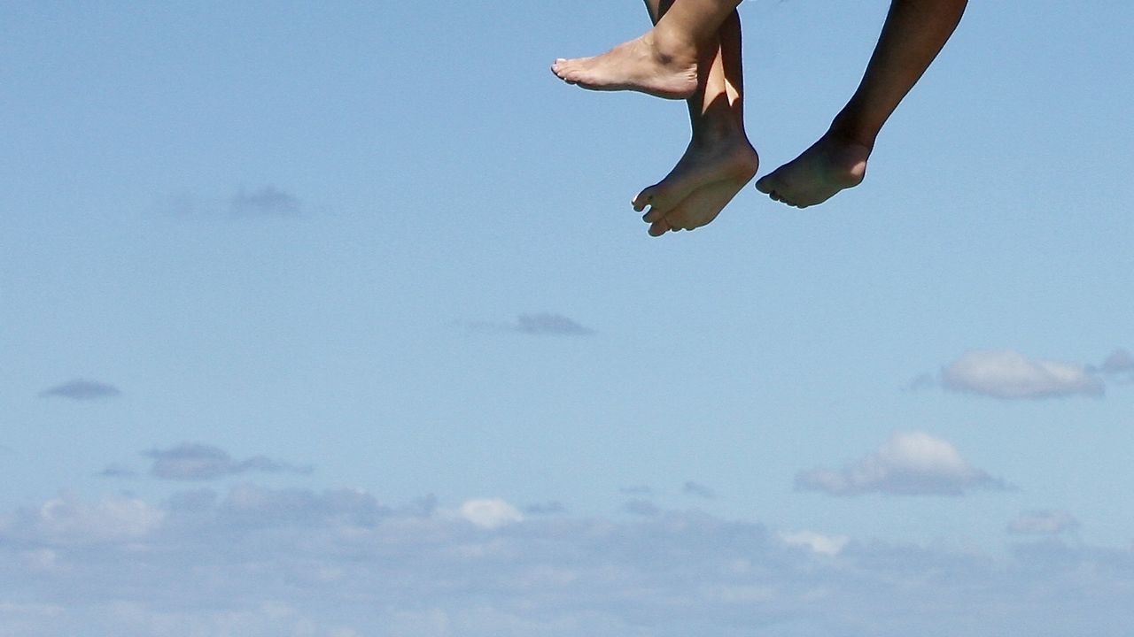 LOW ANGLE VIEW OF PERSON JUMPING AGAINST SKY