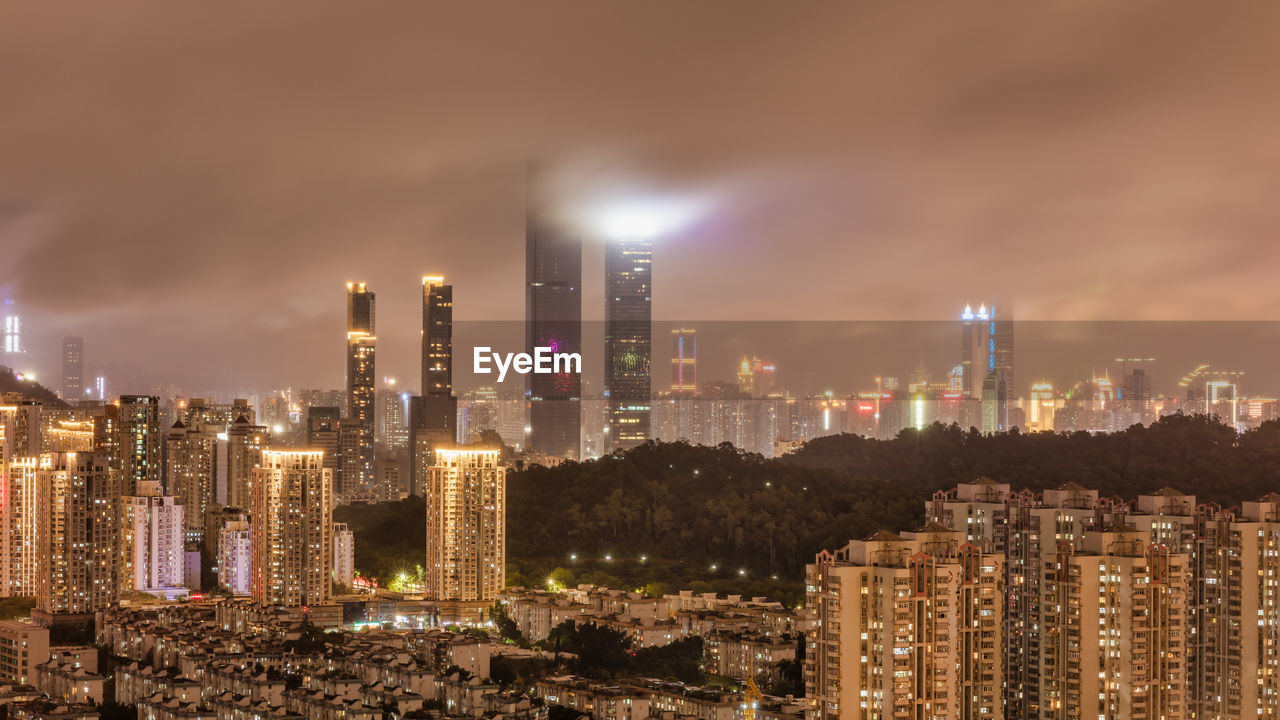 Illuminated buildings in city against sky at night