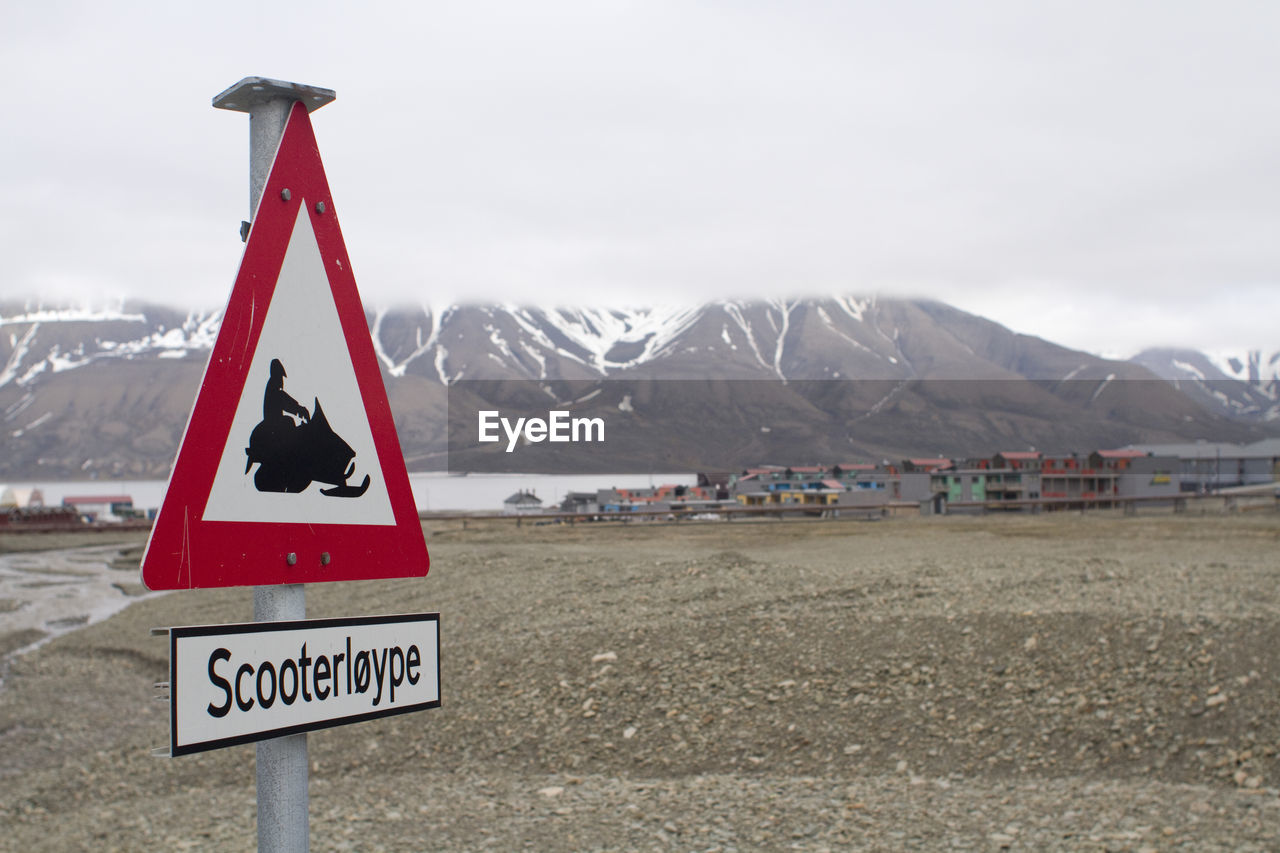 WARNING SIGN ON MOUNTAIN AGAINST SKY