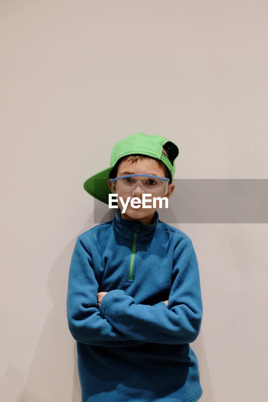 Close-up portrait of boy wearing eyeglasses against white background