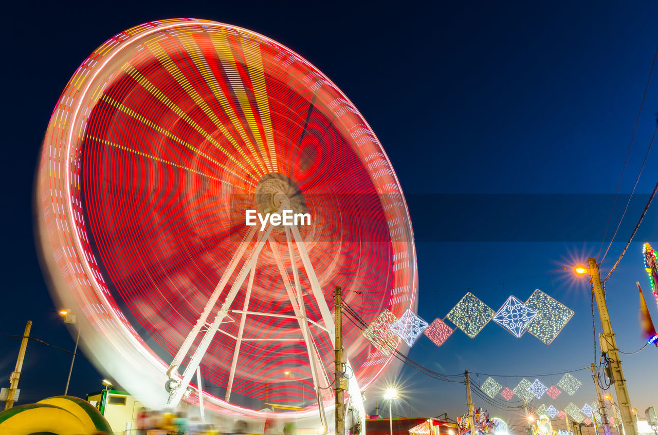 LOW ANGLE VIEW OF ILLUMINATED FERRIS WHEEL AGAINST CLEAR SKY