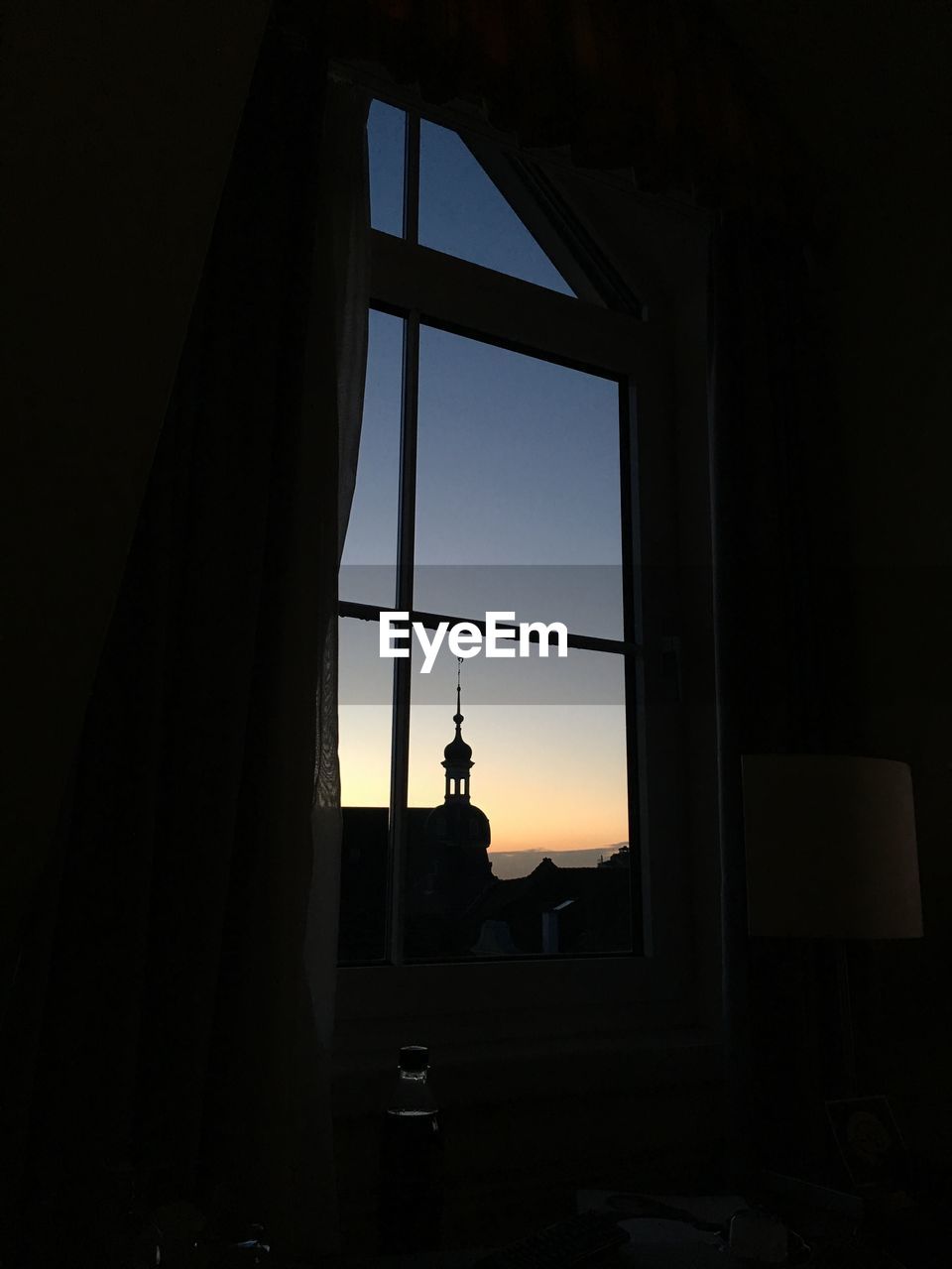 Silhouette building against clear sky seen through glass window at dusk