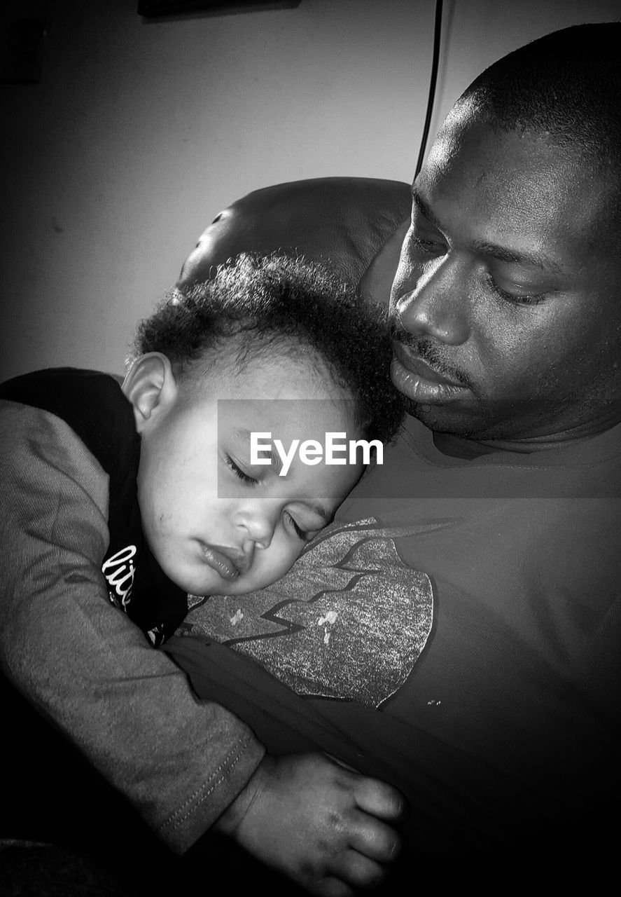 Close-up of baby girl and father resting on chair